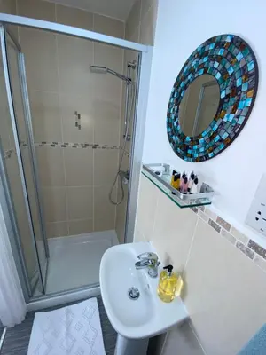 a bathroom with a shower and a sink and a mirror at Beachcomber in Garlieston