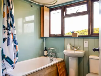a bathroom with a bath tub and a sink at Rosebank Cottage in Borgue