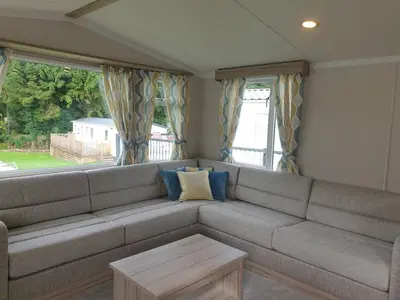 a living room with a large couch with blue pillows at Coral Cabin in Kippford