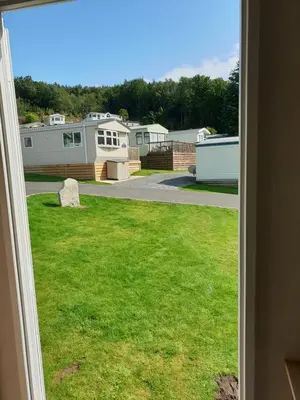 a view from a window of a yard with houses at Coral Cabin in Kippford