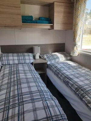 two twin beds in a room with a desk and a window at Coral Cabin in Kippford
