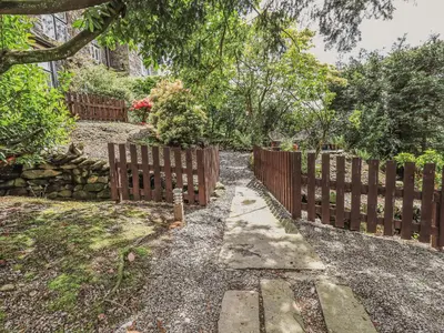 a wooden fence in a yard with a garden at Wisteria in Ambleside