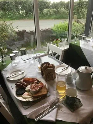 a table with a plate of bread and drinks and a window at Dale View bed & breakfast in Holmrook