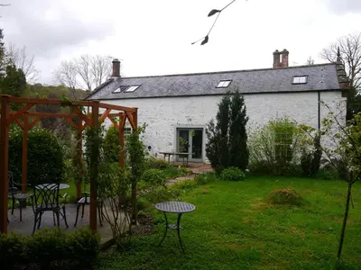 a white house with a table and chairs in a yard at Old Coach House in Moniaive