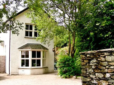 a white house with a window and a stone wall at Stone Beck in Ambleside