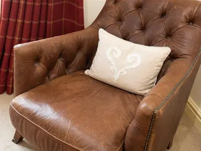 a brown leather chair with a white pillow on it at Stone Beck in Ambleside