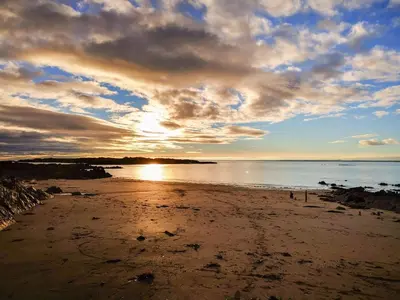 a beach with the sun setting on the water at 9A Church Place in Kirkcudbright