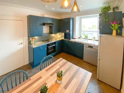 a kitchen with blue cabinets and a wooden table with chairs at 9A Church Place in Kirkcudbright