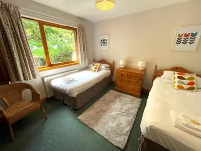a bedroom with two beds and a chair and a window at Beautiful 3BR Lodge - Stunning Beach and Golf Location - Pass the Keys in Dalbeattie