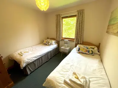 two beds in a small room with a window at Beautiful 3BR Lodge - Stunning Beach and Golf Location - Pass the Keys in Dalbeattie