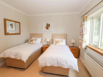 two beds in a room with two windows at Edencroft in Penrith