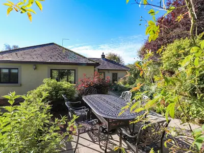 a patio with a table and chairs in a garden at Edencroft in Penrith