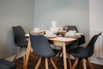 a dining room table with four chairs and a table with wine glasses at The Bailey - Troon - Coorie Doon Stays in Troon