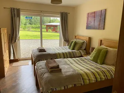 two beds in a room with a window at Gamepark Wood Holiday Cottage in Castle Douglas