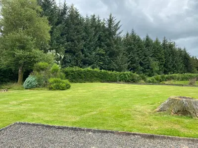 a large grassy field with trees in the background at Gamepark Wood Holiday Cottage in Castle Douglas