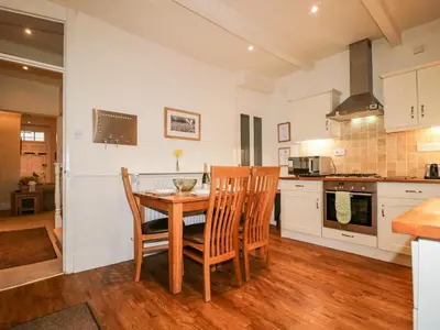 a kitchen with a wooden table and chairs at Raphael's Cottage in Keswick