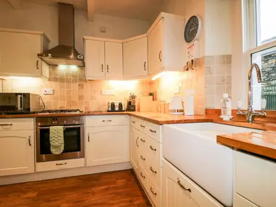 a kitchen with white cabinets and a sink at Raphael's Cottage in Keswick