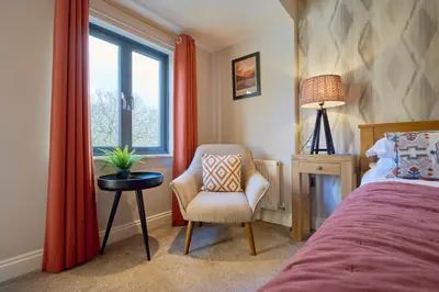 a bedroom with a bed and a chair and a window at Riverside Park 6 in Keswick