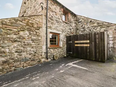 a stone building with a wooden gate in front of it at Lavender Cottage in Penrith