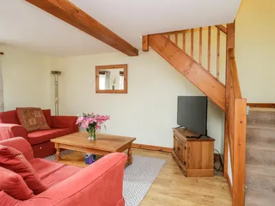 a living room with a red couch and a tv at Lavender Cottage in Penrith