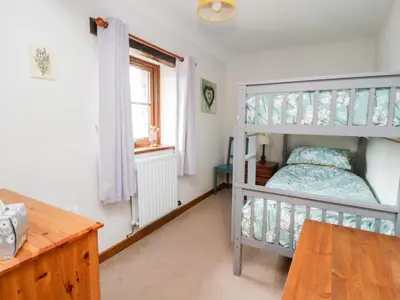 a bedroom with a bunk bed and a desk at Lavender Cottage in Penrith