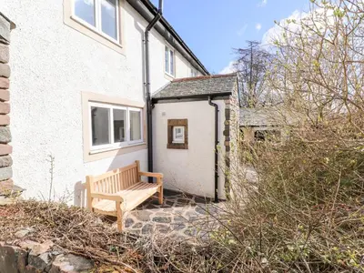 a wooden bench sitting outside of a house at One Town End in Penrith