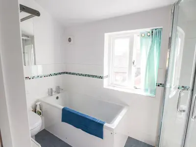 a bathroom with a tub and a toilet and a window at One Town End in Penrith