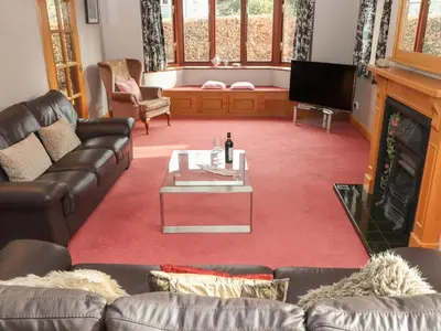 a living room with couches and a table and a television at Beech Nook in Keswick