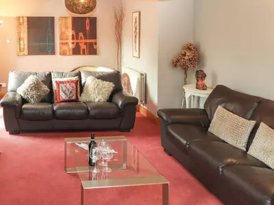 a living room with a leather couch and a table at Beech Nook in Keswick