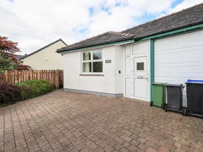 a house with a garage and a brick driveway at Limhus Cottage in Keswick