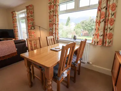 a dining room with a table and chairs and a window at Limhus Cottage in Keswick