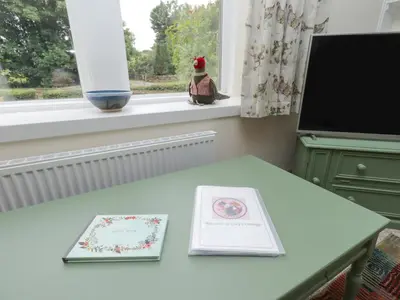 a table with two books on it next to a window at Lucys cottage in Canonbie