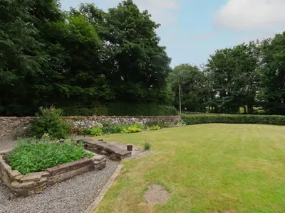 a garden with a stone wall and a lawn at Lucys cottage in Canonbie