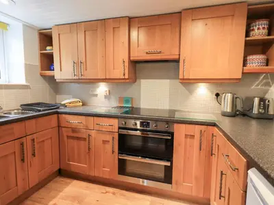 a kitchen with wooden cabinets and a stove at Squirrel Cottage in Keswick