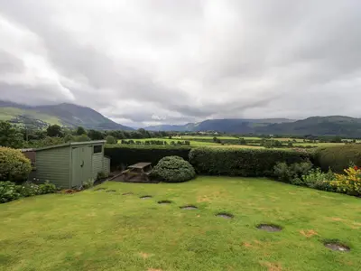 a garden with a shed and mountains in the background at Squirrel Cottage in Keswick