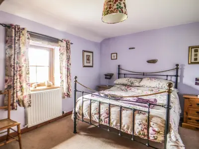 a bedroom with a bed and a window at Daisy Cottage in Penrith
