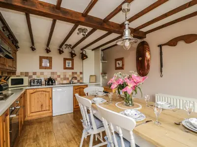 a kitchen with a wooden table with pink flowers on it at Daisy Cottage in Penrith