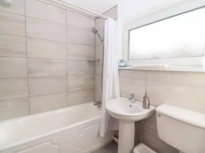 a white bathroom with a sink and a tub and a toilet at Annes Cottage in Keswick