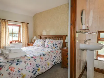 a bedroom with a bed and a sink and a mirror at Poppy Cottage in Penrith