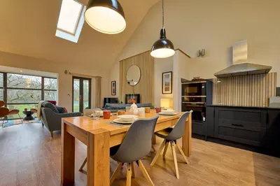a kitchen and living room with a wooden table and chairs at Riverside Park 5 in Keswick