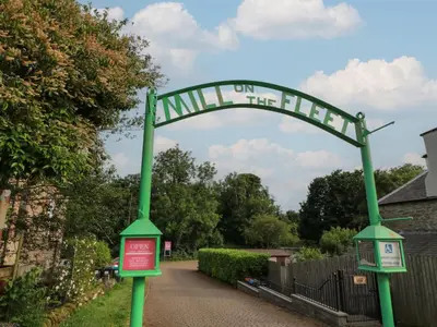 a green sign that says miles on the trail at 2 Fleet Street in Castle Douglas
