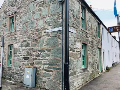 an old stone building with a street sign on it at 2 Fleet Street in Castle Douglas