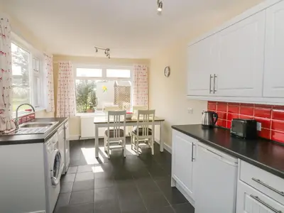 a kitchen with white cabinets and a table with chairs at 7 Cummertrees in Annan