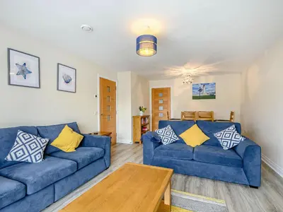 a living room with two blue couches and a table at Oystercatcher in Drummore