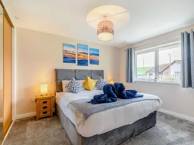 a bedroom with a large bed and a window at Oystercatcher in Drummore
