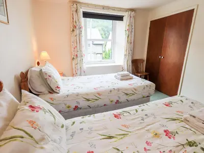 two twin beds in a bedroom with a window at 7 Stybarrow Terrace in Penrith