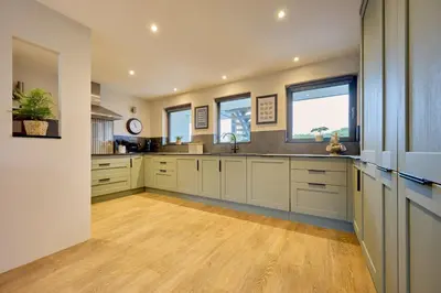 a large kitchen with white cabinets and wooden floors at Riverside Park 3 in Keswick