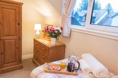 a bedroom with a tray of food on a bed at Honeybee Cottage in Penrith