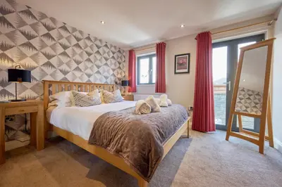 a bedroom with a large bed with red curtains at Riverside Park 4 in Keswick