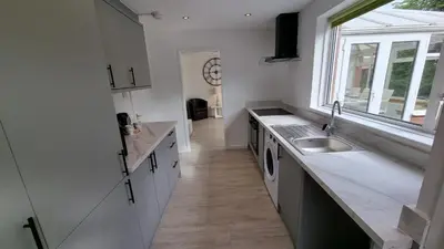 a kitchen with white cabinets and a sink and a window at Rozelle Villa in Ayr